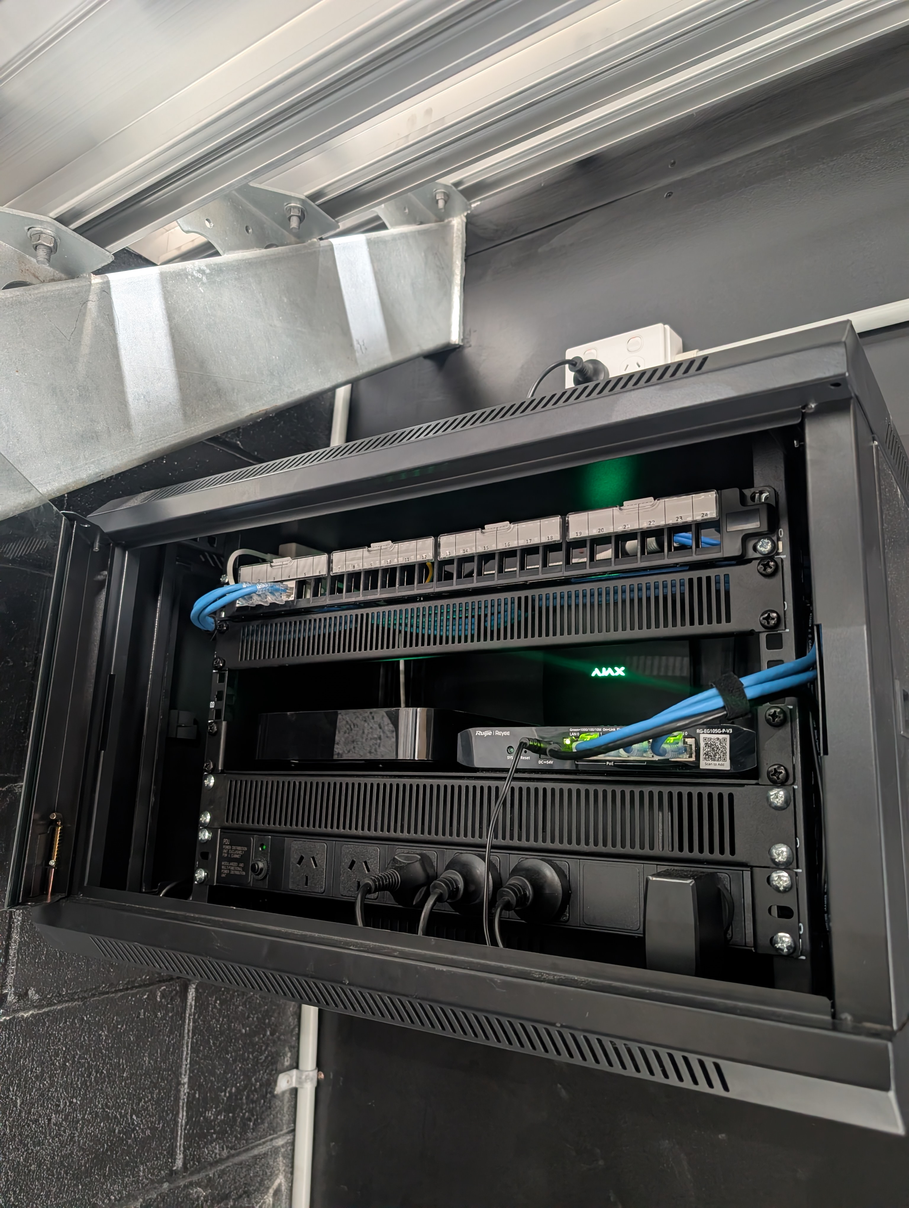 Wall-mounted network rack with patch panel and PoE switching